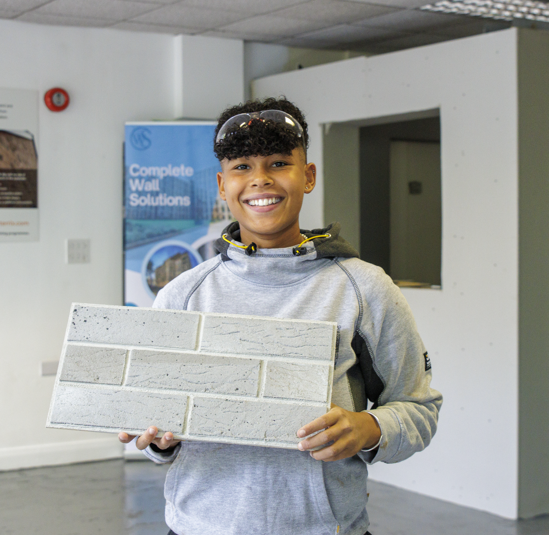 A young lady stands smiling holding a brickslip sample