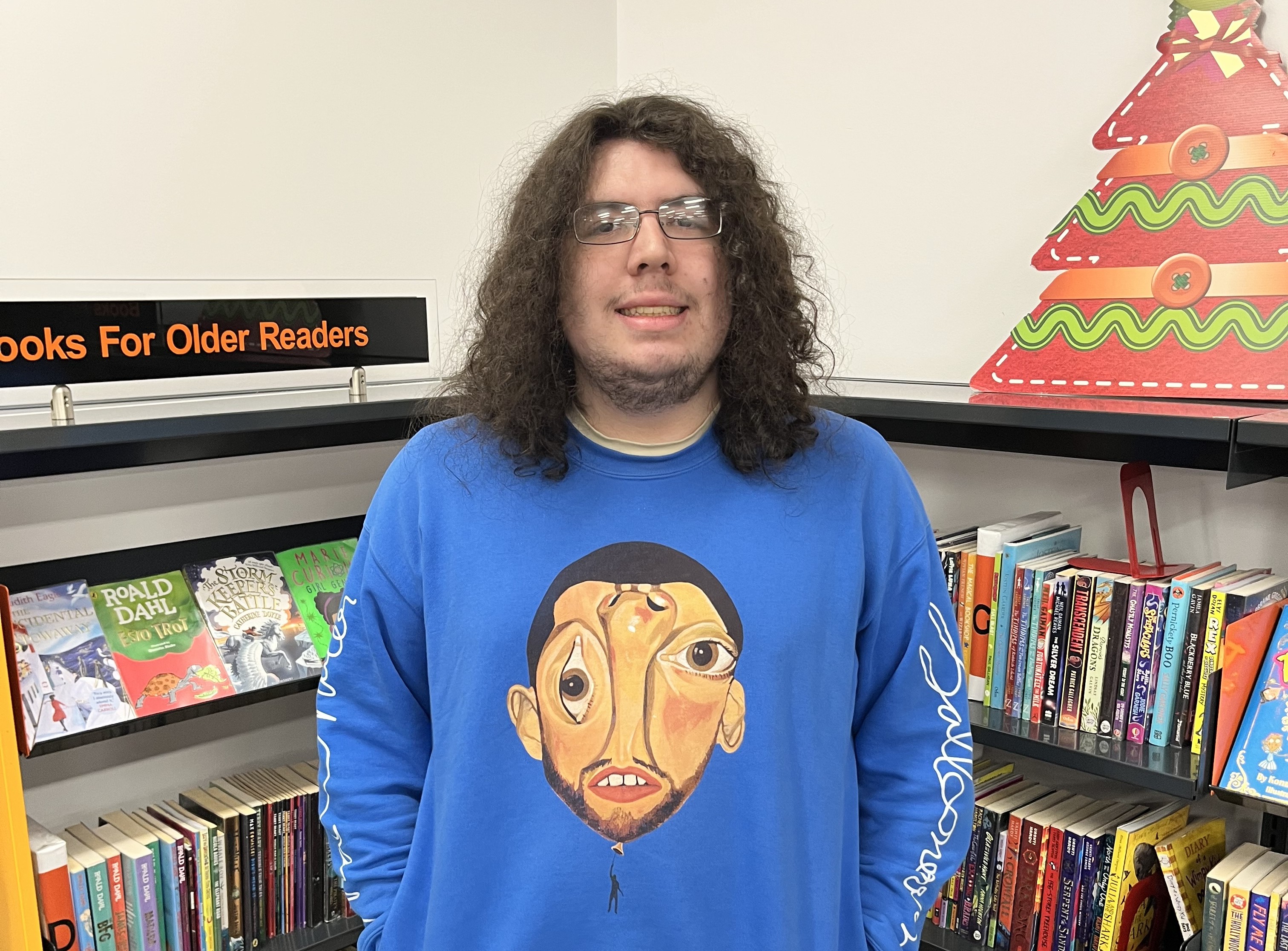 A person stood in front of some bookshelves smiling