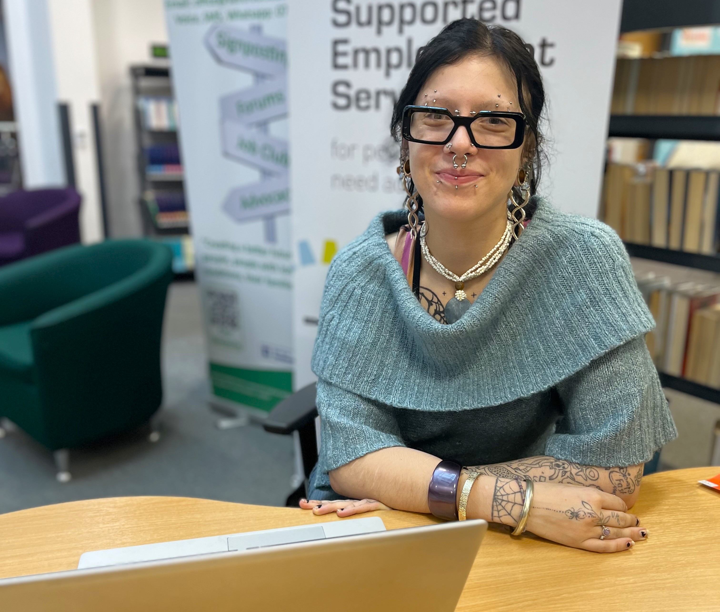 A photo of a woman sat smiling at a desk