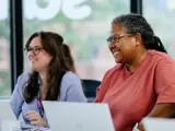 Two women sat at a desk with laptops