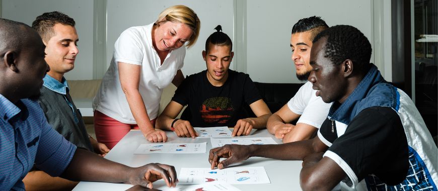 A group of young men sat round a table learning English