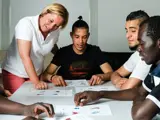A group of young men sat round a table learning English