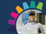 Young person smiling broadly, holding a sign that looks like bricks